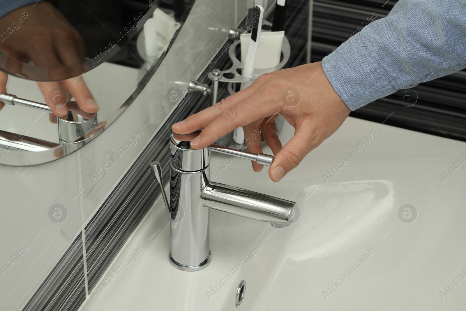 Photo of Man using water tap in bathroom, closeup