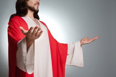 Photo of Jesus Christ with outstretched arms on light grey background, closeup