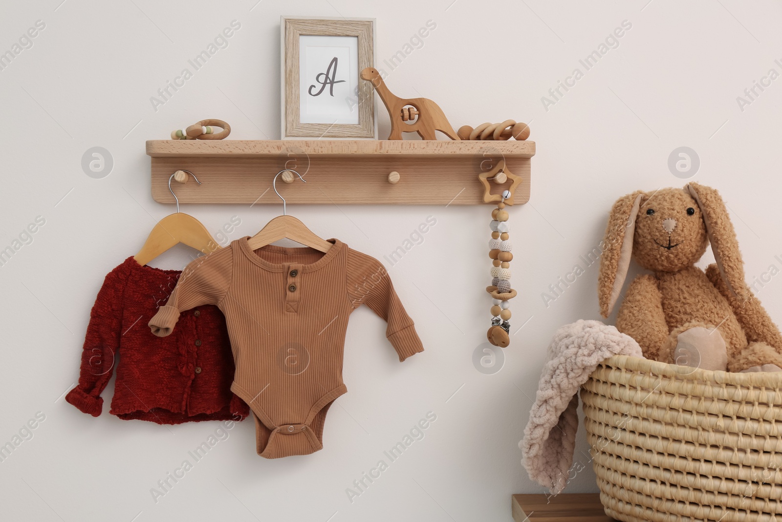 Photo of Wooden shelf with baby clothes, toys and accessories in room. Interior design