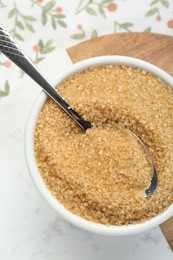 Photo of Brown sugar in bowl and spoon on table, top view