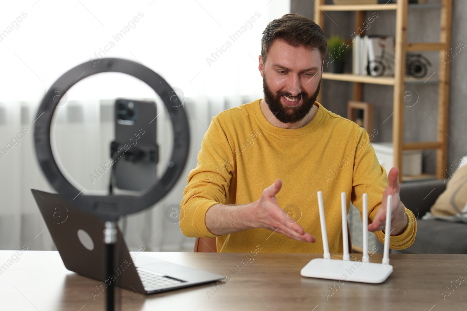 Photo of Smiling technology blogger recording video review about WI-FI router at home