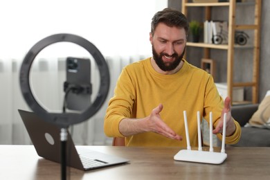 Smiling technology blogger recording video review about WI-FI router at home