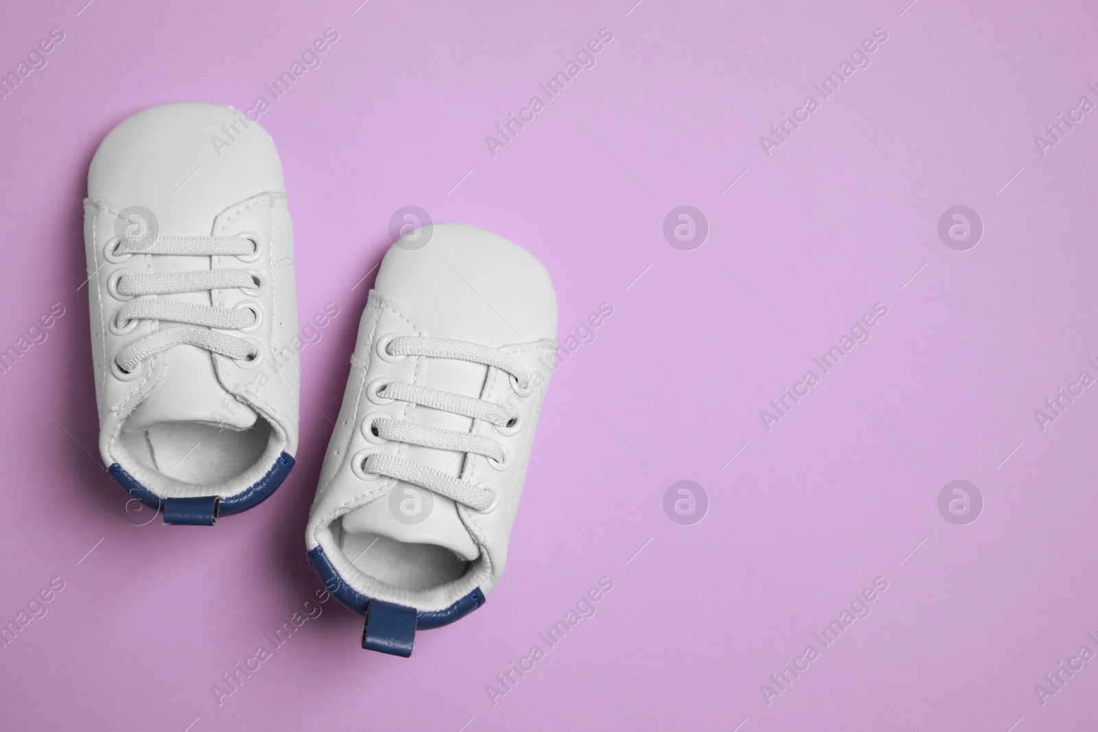 Photo of Cute baby shoes on violet background, flat lay. Space for text