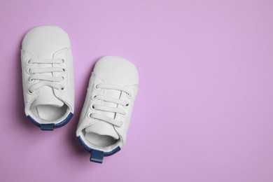 Cute baby shoes on violet background, flat lay. Space for text