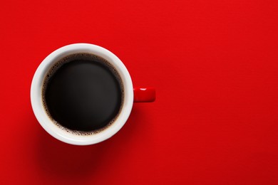 Photo of Cup with aromatic coffee on red background, top view. Space for text