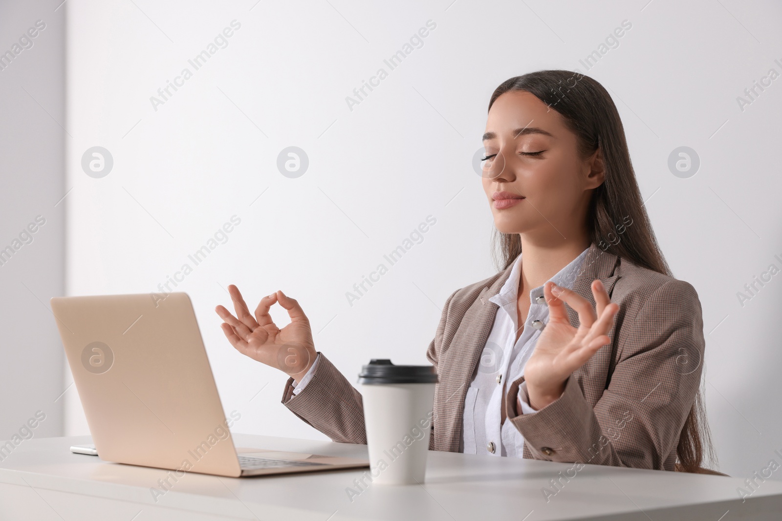 Photo of Find zen. Woman taking break from work at table near white wall