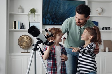 Photo of Happy father and children using telescope to look at stars in room