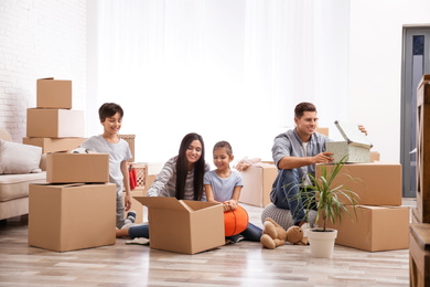 Happy family unpacking moving boxes at their new home