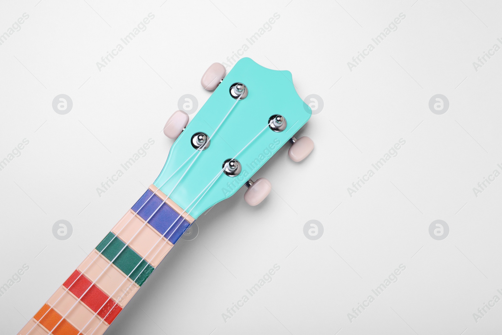 Photo of Colorful ukulele neck on white background, top view. String musical instrument