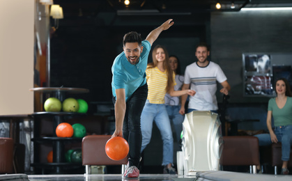 Photo of Young man throwing ball and spending time with friends in bowling club