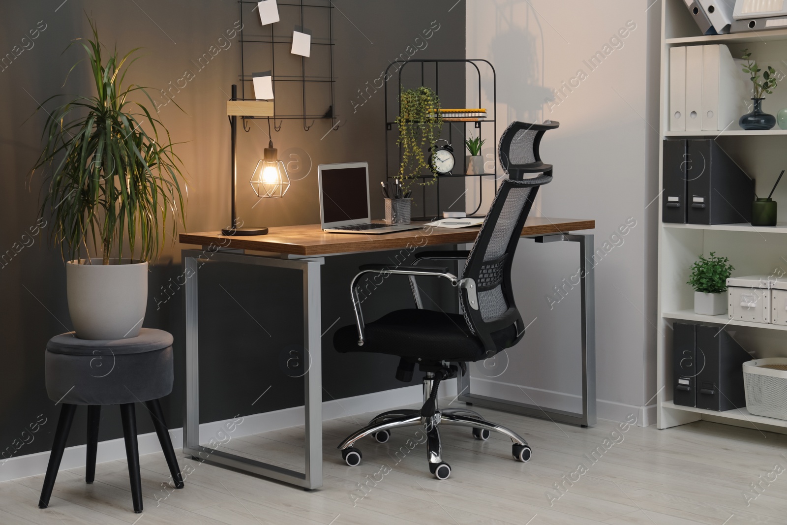 Photo of Cozy workplace with modern laptop on desk and comfortable chair at home