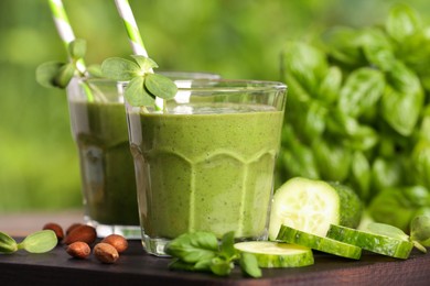Photo of Glasses of fresh green smoothie and ingredients on wooden board