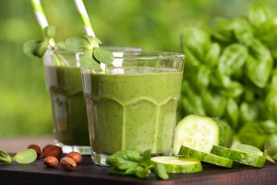 Glasses of fresh green smoothie and ingredients on wooden board