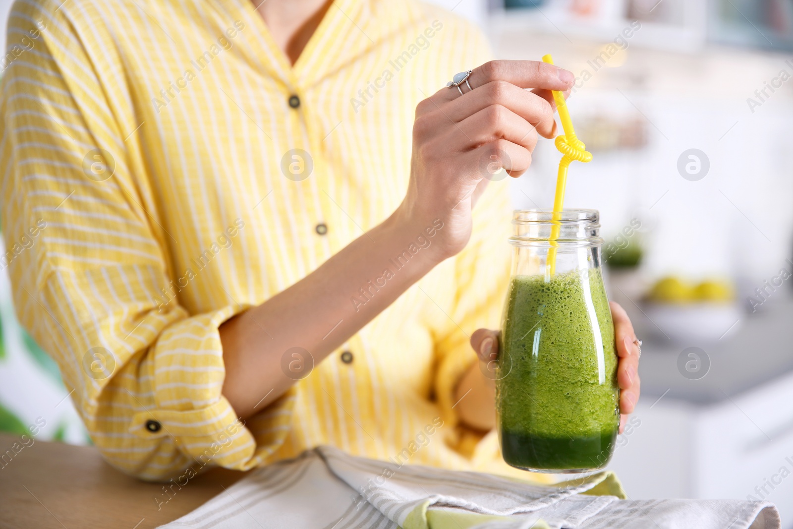 Photo of Young woman with bottle of healthy smoothie at table, closeup