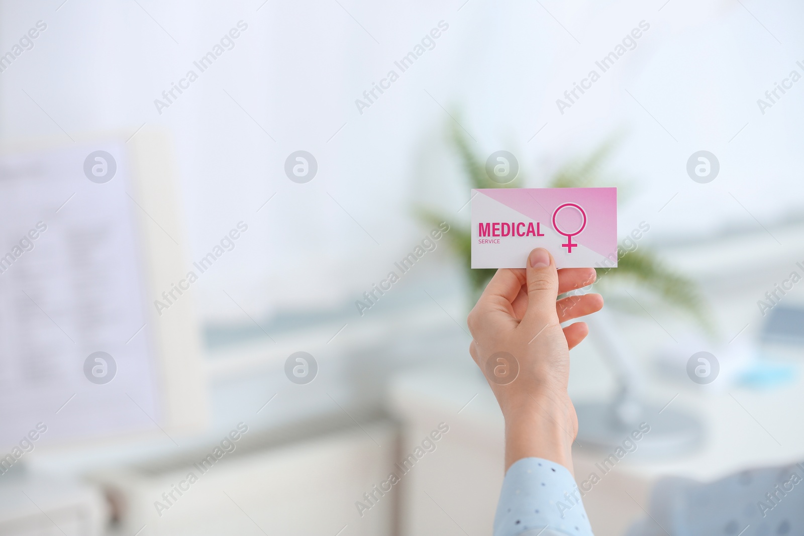 Photo of Girl holding medical business card indoors, closeup with space for text. Women's health service