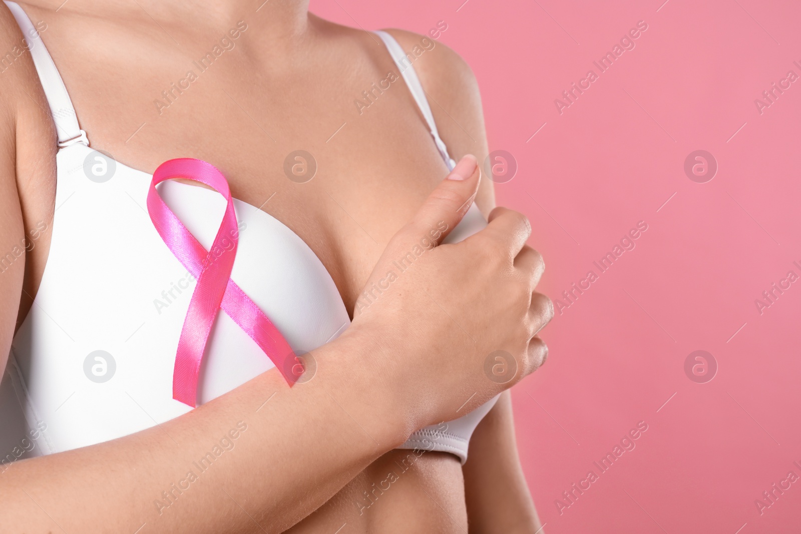 Photo of Woman with pink ribbon on color background, closeup. Breast cancer awareness