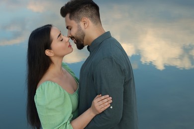 Photo of Romantic date. Beautiful couple kissing near lake