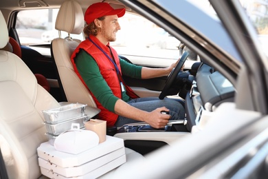 Male courier with orders in car. Food delivery service