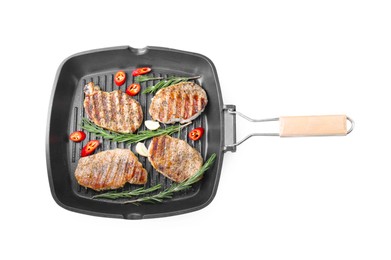 Photo of Grill pan with delicious pork steaks, garlic, chili pepper and rosemary isolated on white, top view