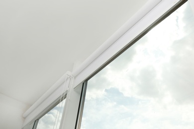 Modern window with white roller blinds indoors, low angle view