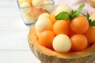 Different melon balls with mint on white table, closeup