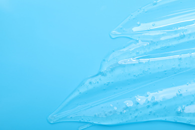 Photo of Pure transparent cosmetic gel on light blue background, top view