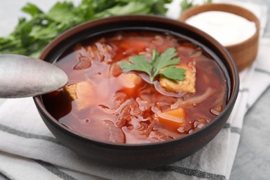 Photo of Bowl of delicious borscht on light grey table, closeup