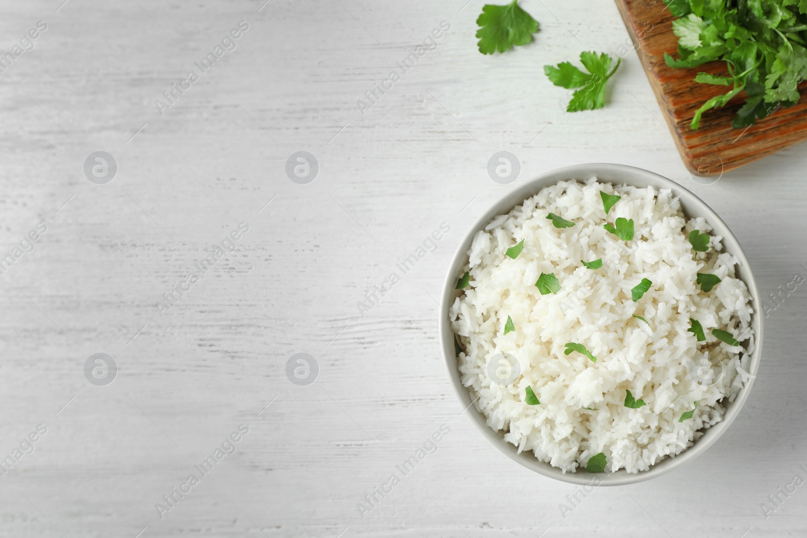 Photo of Bowl of boiled rice served on wooden table, top view with space for text