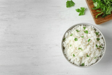 Photo of Bowl of boiled rice served on wooden table, top view with space for text