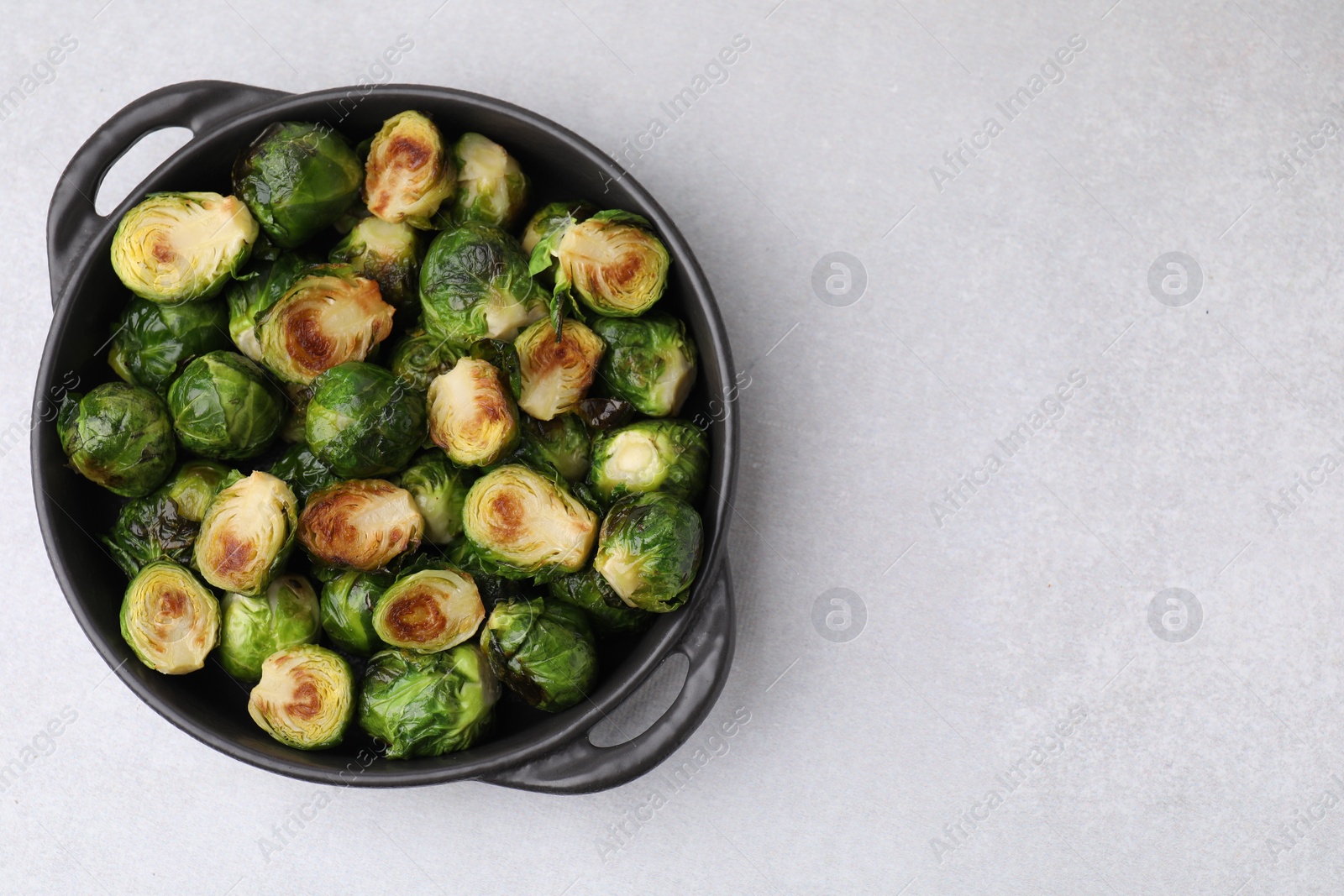 Photo of Delicious roasted Brussels sprouts in baking dish on light table, top view. Space for text