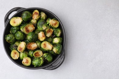 Photo of Delicious roasted Brussels sprouts in baking dish on light table, top view. Space for text