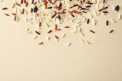 Photo of Mixed brown and other types of rice on color background, top view with space for text