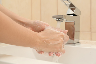 Woman washing hands with antiseptic soap in bathroom, closeup
