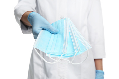 Doctor in latex gloves holding disposable face masks on white background, closeup. Protective measures during coronavirus quarantine