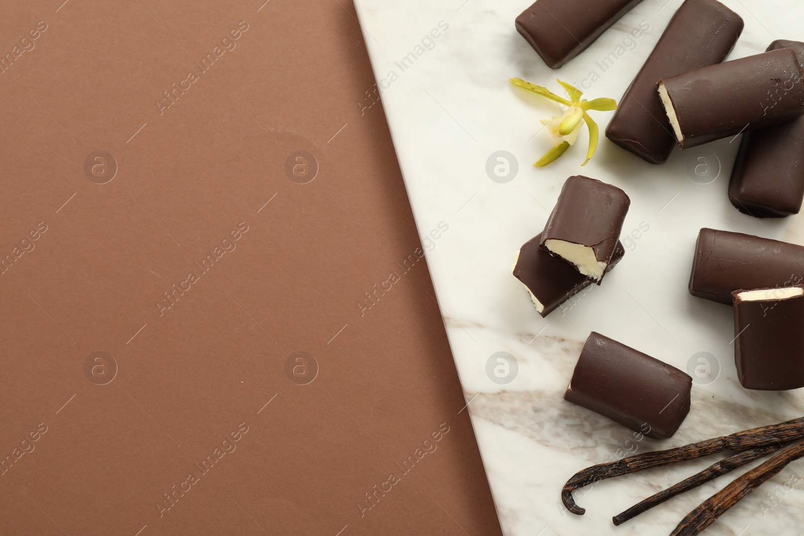 Photo of Glazed curd cheese bars, vanilla pods and flower on light brown background, top view. Space for text