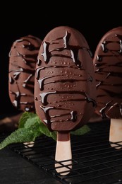 Photo of Delicious glazed ice cream bars and mint on black table
