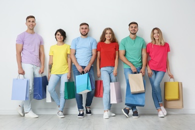Photo of Group of young people with shopping bags near light wall