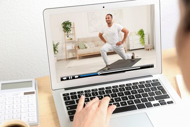 Image of Woman watching morning exercise video on laptop at table, closeup