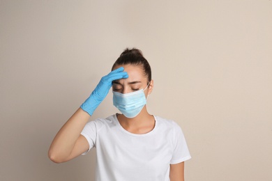 Photo of Stressed woman in protective mask on beige background. Mental health problems during COVID-19 pandemic