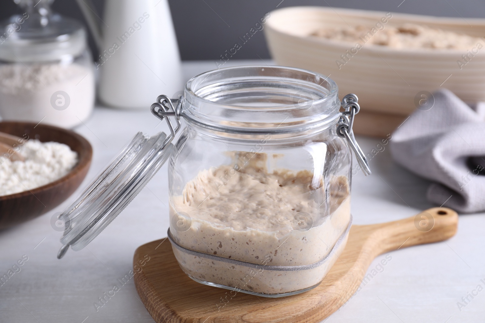 Photo of Sourdough starter in glass jar on light table, closeup