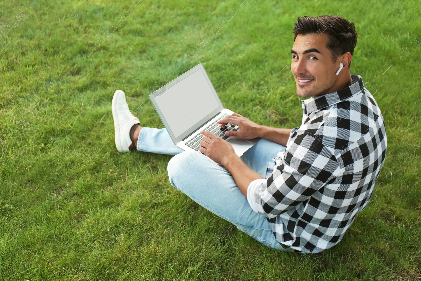 Photo of Portrait of young man with laptop outdoors. Space for design