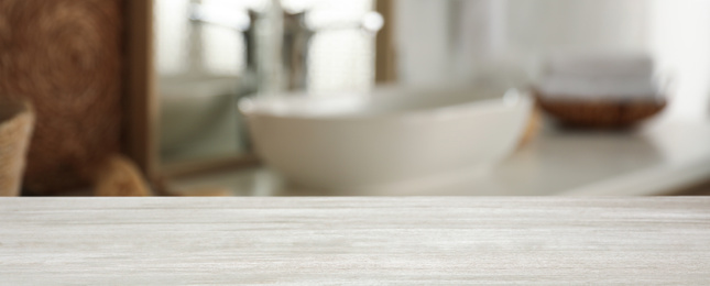 Empty wooden table and blurred view of stylish bathroom interior