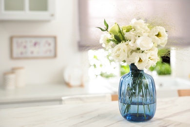 Bouquet of beautiful eustoma flowers on white table in kitchen. Interior design