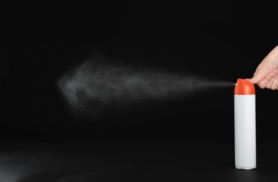 Photo of Woman spraying air freshener on black background, closeup