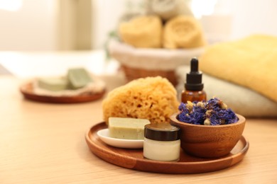 Dry flowers, loofah, soap bar, bottle of essential oil and jar with cream on wooden table indoors. Spa time