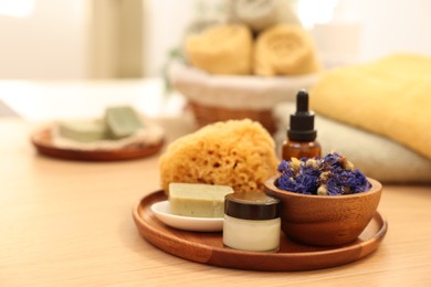 Photo of Dry flowers, loofah, soap bar, bottle of essential oil and jar with cream on wooden table indoors. Spa time