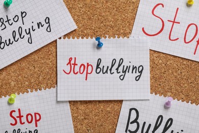 Photo of Notes with phrase Stop Bullying pinned to cork board, closeup
