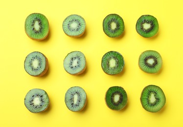 Photo of Cut fresh ripe kiwis on yellow background, flat lay