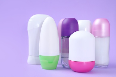 Composition with different female deodorants on purple background, space for text