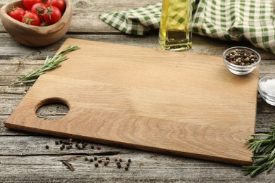 Photo of Cutting board, rosemary, oil and pepper on wooden table. Space for text